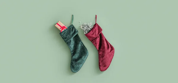 stock image Christmas socks with gifts hanging on light green wall