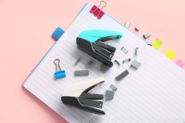 Pembe arka planda zımba, zımba ve defterleri aç