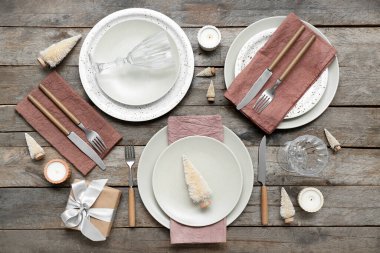 Noel ağaçları, hediyeler ve ahşap arka planda mumlarla dolu güzel bir masa.