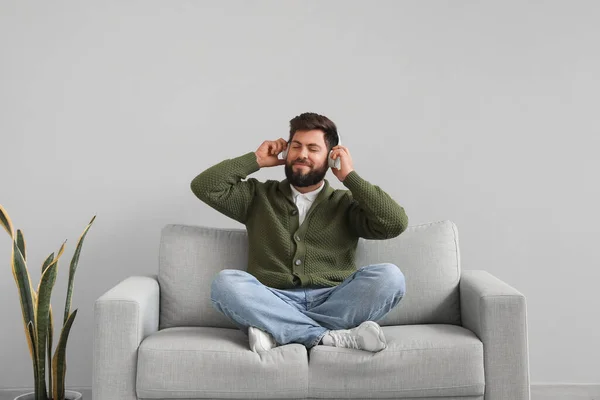 Handsome Bearded Man Headphones Sitting Grey Sofa Light Wall — Stock Photo, Image