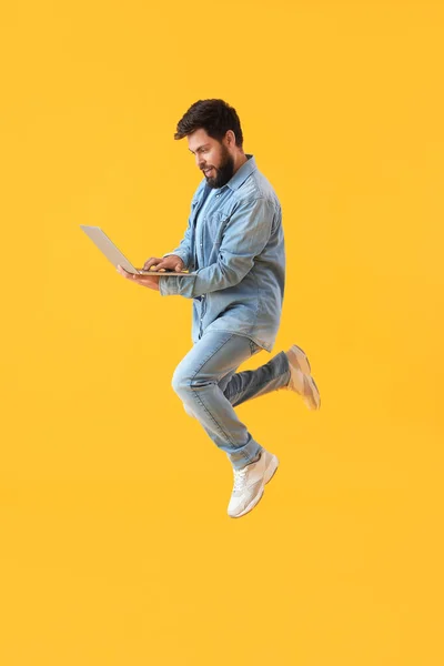 Красивый Бородатый Мужчина Ноутбуком Прыгает Желтом Фоне — стоковое фото