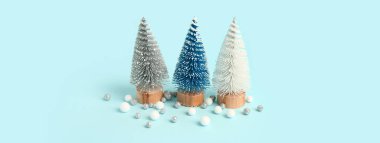 Dekoratif Noel ağaçları ve açık mavi arka planda toplar