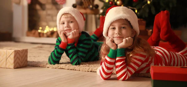 圣诞前夕 穿着圣诞老人帽和睡衣的可爱的孩子们在家里 — 图库照片