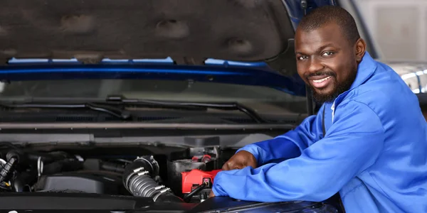 African-American mechanic repairing car in service center
