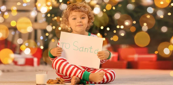 Cute little child with letter to Santa and treats at home