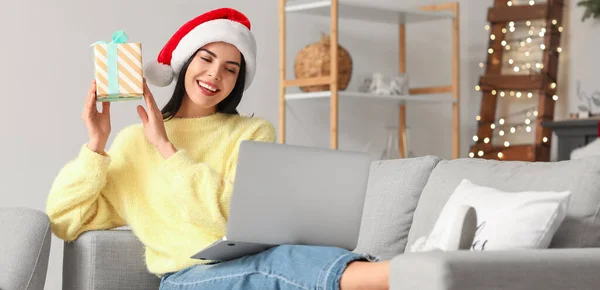 Young woman with laptop celebrating Christmas at home due to coronavirus epidemic