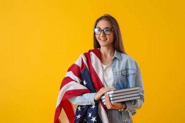 Amerikan bayrağı ve sarı arka plan kitapları olan güzel bir kadın.