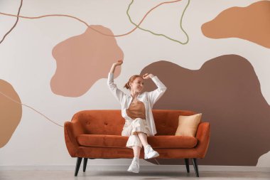 Renk duvarının yanındaki kırmızı koltukta oturan güzel kadın.