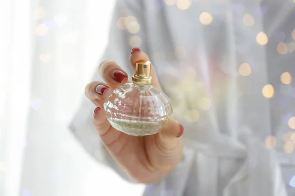 Woman with bottle of luxury perfume, closeup