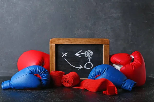 Chalkboard with drawn scheme of boxing game, gloves and bandages on dark background