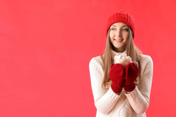 戴着暖帽 背景为红色的玻璃杯可可的年轻女子 — 图库照片
