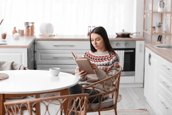 Ung Kvinde Læser Bog Ved Spisebordet Køkkenet - Stock-foto