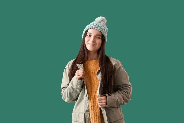 若いです女性で暖かい帽子とジャケットで緑の背景 — ストック写真