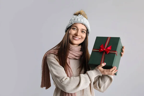 若いです女性で暖かいです帽子とともにクリスマスプレゼント上の灰色の背景 — ストック写真