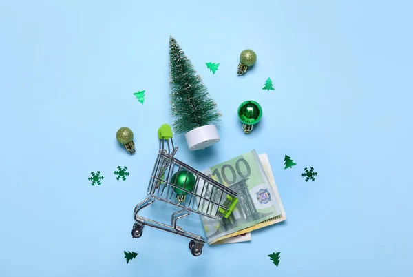 青い背景にクリスマスボール お金とモミの木とショッピングカート — ストック写真