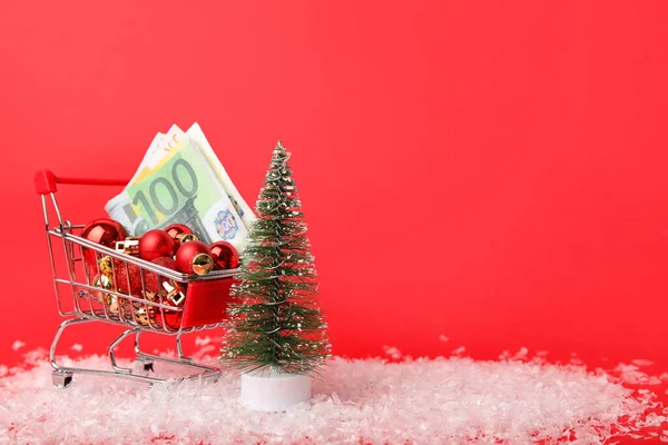 Shopping Cart Money Christmas Balls Snow Fir Tree Red Background — Stock Photo, Image