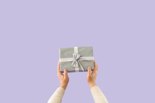Man with Christmas gift box on lilac background