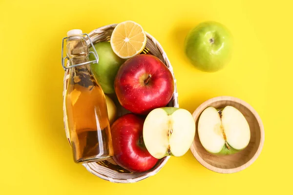 装苹果果醋和黄色背景水果的篮子 — 图库照片