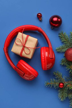 Modern kulaklıklı kompozisyon, Noel hediyesi, toplar ve mavi arka planda köknar dalları