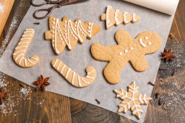 Lezzetli Noel kurabiyeleri ve ahşap arka planda baharatlar olan kağıt pişirme, yakın plan.