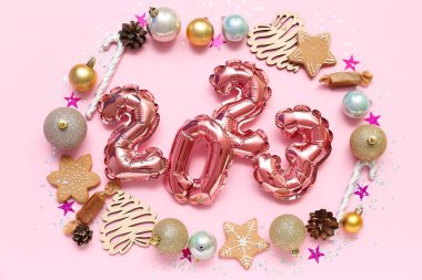 2023 noel süslü folyo balonlardan yapılmış ve pembe arka planda ikramlar.