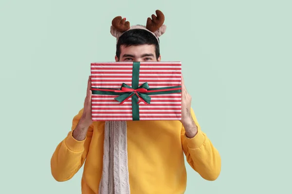 Счастливый Молодой Человек Оленьих Рогах Рождественским Подарком Зеленом Фоне — стоковое фото