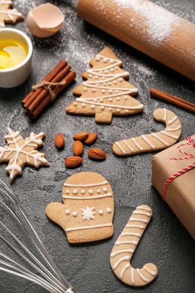 Tasty Christmas cookies and ingredients on dark background, closeup