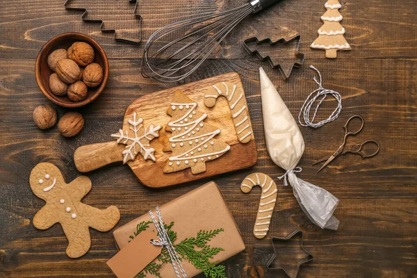 Composition with tasty Christmas cookies, gift and utensils on wooden background