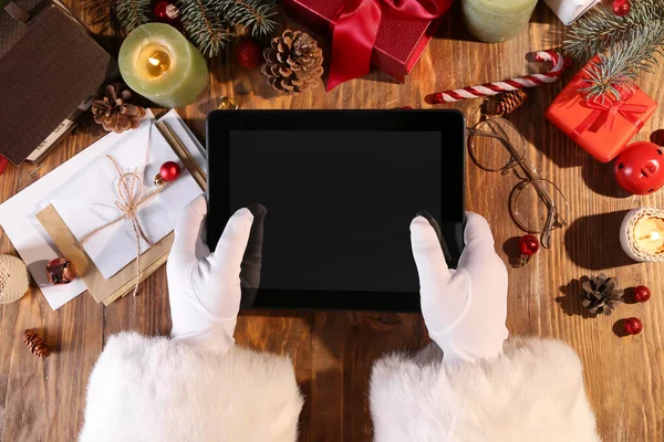 Jultomten Håller Tablett Dator Träbord Med Juldekor Och Presenter Ovanifrån — Stockfoto