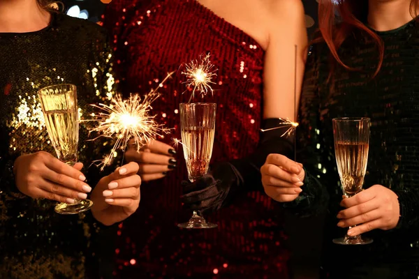 Yanan Noel Maytapları Şampanya Bardakları Olan Zarif Elbiseli Genç Kadınlar — Stok fotoğraf