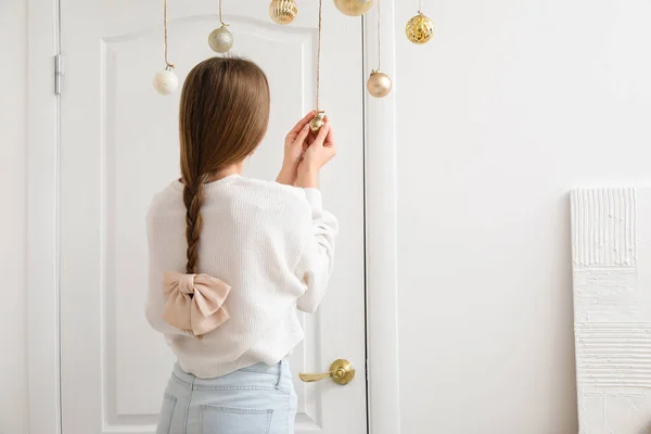 Jonge Vrouw Met Kerstballen Versierd Witte Deur Thuis — Stockfoto