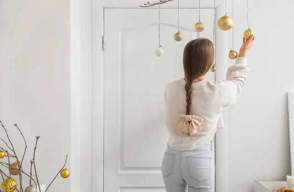 Jonge Vrouw Met Kerstballen Versierd Witte Deur Thuis Achteraanzicht — Stockfoto