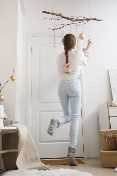家で白いドアを飾るクリスマスボールを持つ若い女性 バックビュー — ストック写真