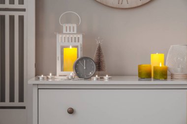 Çalar saat, Noel feneri ve oturma odasındaki çekmecelerin üstünde yanan mumlar.