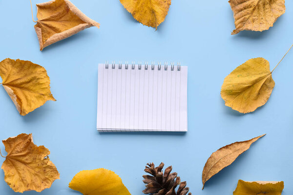 Composition with blank notebook, autumn leaves and pine cone on color background