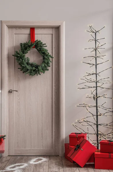 Drzwi Drewniane Wieńcem Świątecznym Świecącą Lampą Prezentami Salonie — Zdjęcie stockowe