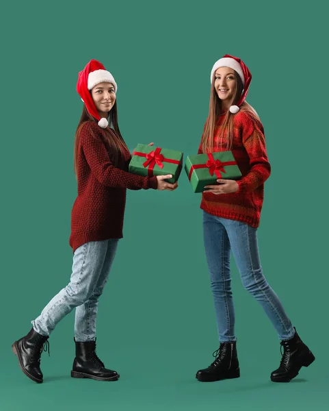Junge Frauen Nikolausmützen Mit Weihnachtsgeschenken Auf Grünem Hintergrund — Stockfoto