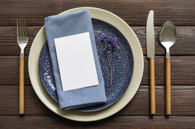 Boş kartıyla masa ayarları ve koyu ahşap arka planda çiçek dekoru