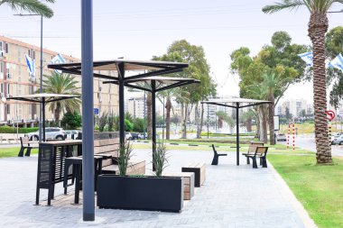 Şehir sokaklarında modern banklar ve şemsiyeler