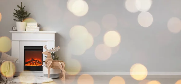 Interior of light room with fireplace and Christmas decor near light wall