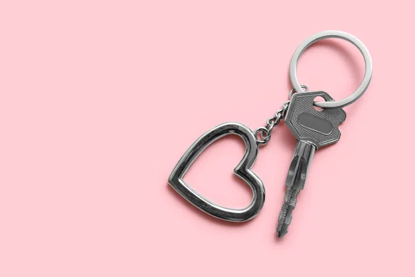 Key with heart shaped keychain on pink background
