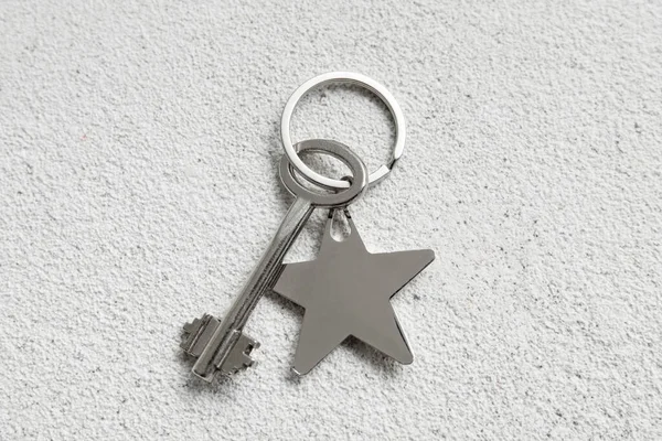 Key with star shaped keychain on light background