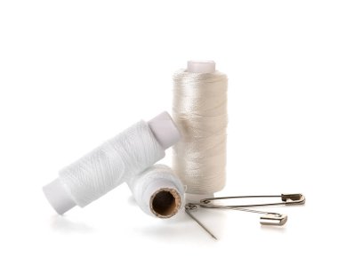 Beyaz arkaplanda izole edilmiş iplik makaraları ve iğneler