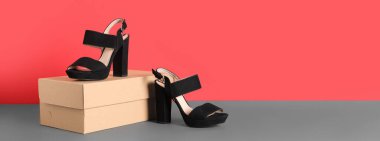 Kırmızı duvarın yanındaki masada karton kutu ve yüksek topuklu sandaletler. Tasarım için pankart