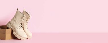 Pembe zemin üzerinde şık çizmeleri olan karton kutu ve metin için boşluk