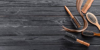 Farklı kuaför aletleri ve koyu ahşap zemin üzerinde sarı saç teli metin için yer, üst görünüm