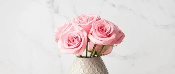 Beautiful pink roses in vase on light background, closeup