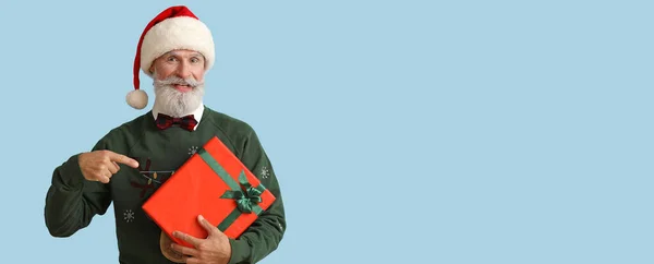 Старший Человек Шляпе Санты Держит Рождественский Подарок Светло Голубом Фоне — стоковое фото