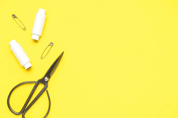 stock image Thread spools, pins and scissors on yellow background