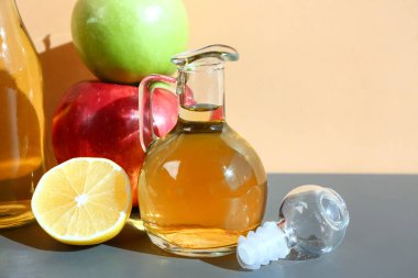 Renk duvarının yanındaki masada elma sirkesi ve meyveler, yakın plan.